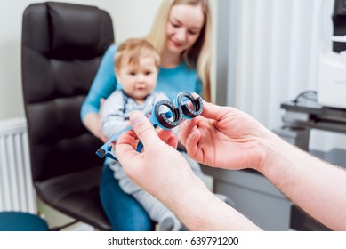 Basic Eye Examination. Mother Holds Child During Eye Exam In Clinic