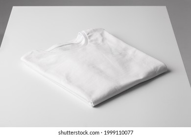 Basic Folded White Tshirt On Grey Table. Mock Up For Branding T-shirt. Monochrome Trend. 