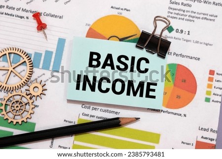 BASIC INCOME text on a notebook on green paper.