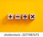 Basic mathematical operations symbols. Plus, minus, multiply and divide symbols on wooden cubes on yellow background. Mathematic or math education and basic calculations for business concept.