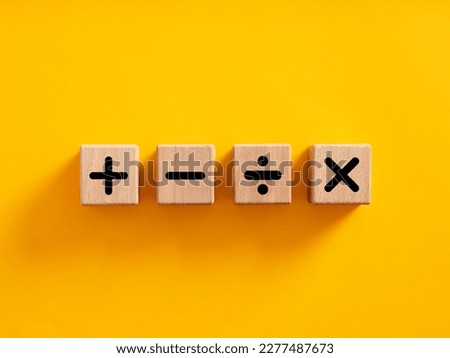 Basic mathematical operations symbols. Plus, minus, multiply and divide symbols on wooden cubes on yellow background. Mathematic or math education and basic calculations for business concept.