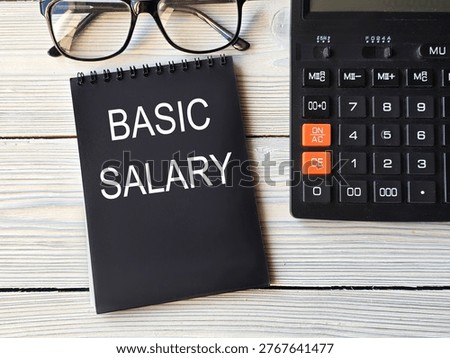 BASIC SALARY - words in black notebook with calculator background. Business concept