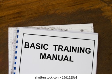 Basic Training Manual With Blueprints In A Wood Texture Background.