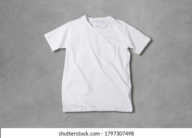 Basic White Tshirt On Grey Concrete Background. Mock Up For Branding T-shirt With Pocket. 