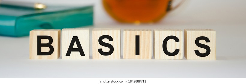  BASIC Words Made From Wooden Cubes On The Back Of A Notebook And Tea. Go Back To Basics Or Simplify Your Business Concept. High Quality Photo