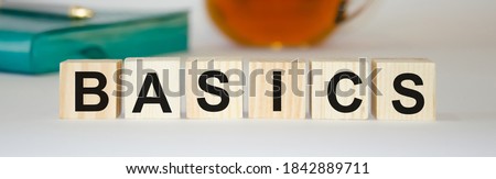  BASIC words made from wooden cubes on the back of a notebook and tea. Go back to basics or simplify your business concept. High quality photo