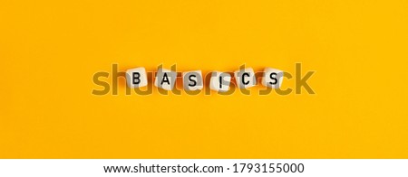 Basics word written on wood blocks on yellow background with flat lay view. Back to basics or simplifying business concept. 