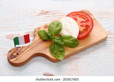 Basil leaf, mozzarella cheese, tomato slice and Italy flag, top view