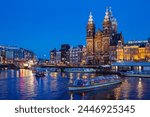 Basilica of Saint Nicholas with canal cruise in Amsterdam at night, Netherlands