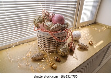 Basket With Beautiful Christmas Tree Baubles And Fairy Lights On Window Sill Indoors