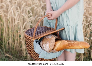 Basket With Bread And Baguette, Child Holds Basket With Freshly Baked Bread In Front Of Wheat Field On Sunset