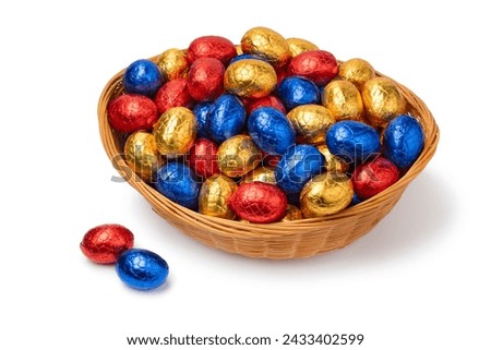 Basket with Chocolate easter eggs in colorful tinfoil close up isolated on white background 