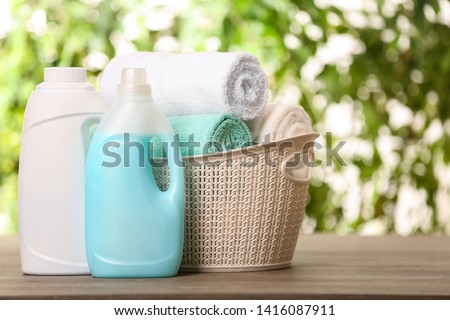 Basket with clean towels and detergents on table against blurred background. Space for text