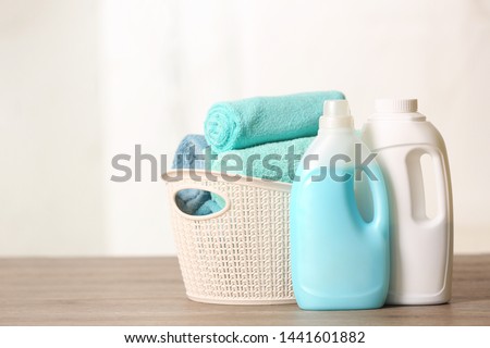 Basket with clean towels and detergents on table. Space for text
