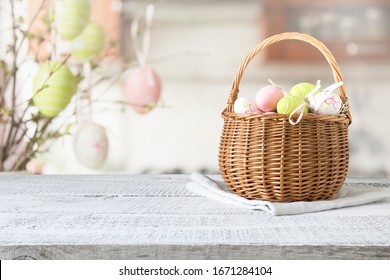 Basket with colorful pastel eggs on kitchen wooden tabletop. Spring easter composition. Space for text or design.