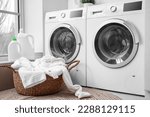 Basket with dirty clothes near washing machines in laundry room