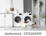 Basket with dirty clothes near washing machines in laundry room