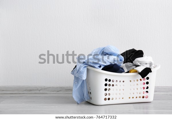 Basket\
with dirty laundry on floor against light\
wall