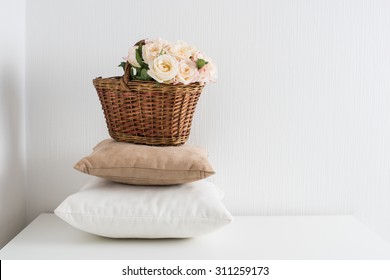 Basket With Flowers On A Pile Of Pillows By The White Wall, A Cozy Home Decor