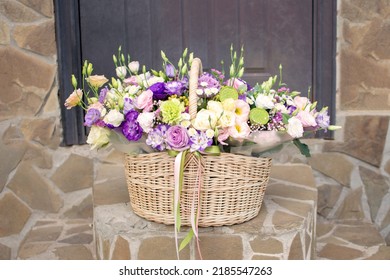 A Basket Of Flowers On The Steps In Front Of The Front Door. High Quality Photo