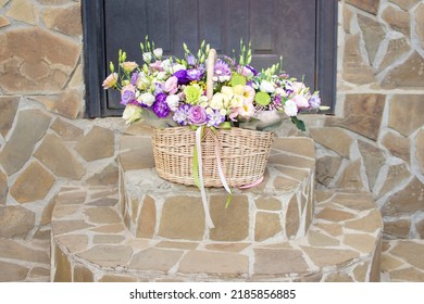 A Basket Of Flowers On The Steps In Front Of The Front Door. High Quality Photo