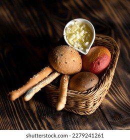 Basket with fresh pastries and butter. Bread sticks and buns in wicker basket on table. Breakfast. Wooden background. View from above. Copy space.  - Powered by Shutterstock