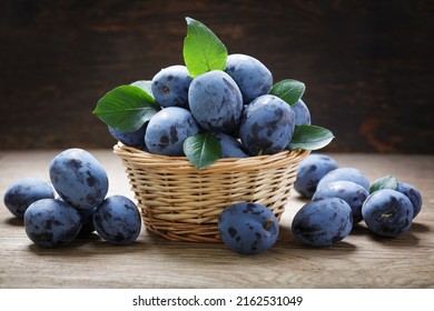 basket of fresh ripe plums on a wooden background