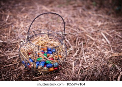 Basket full of easter chocolates eggs on a  undergrowth. 