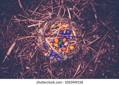Basket full of easter chocolates eggs on a  undergrowth. 