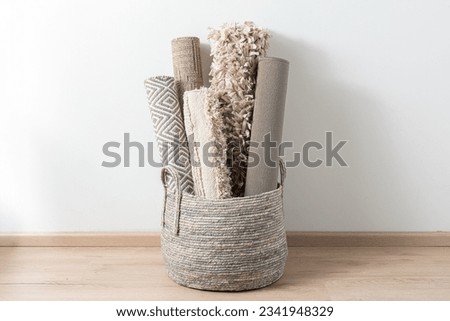 a basket full of a set of rolled rugs with different textures and designs, inside a room
