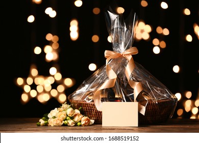 Basket with gifts and flowers for Mother's Day on table against dark background