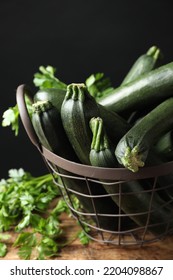 Basket with green zucchinis on wooden table, closeup