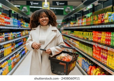 With a basket in hand a beautiful curly hair black woman searching and buying groceries in super market. - Powered by Shutterstock