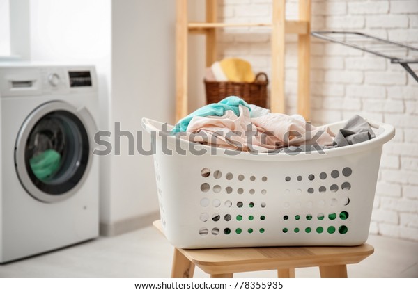 Basket with laundry on stool and washing machine\
in bathroom