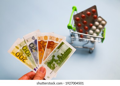 basket with medicines, pills, capsules and euro banknotes in hand, money, conceptual cost of medicines