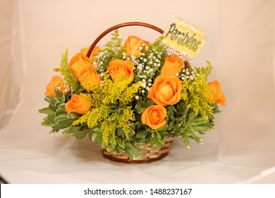 Basket of orange roses flwoers with plaque written in Portuguese "Congratulations". 
