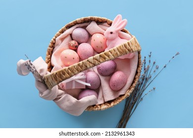 Basket with painted Easter eggs, lavender and bunny on blue background