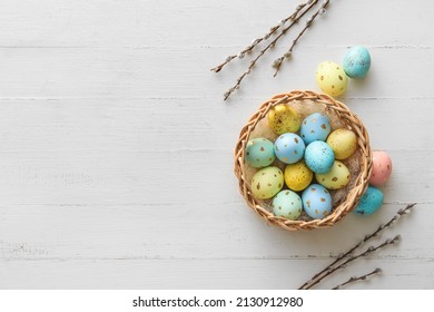 Basket with painted Easter eggs and willow branches on light wooden background - Powered by Shutterstock