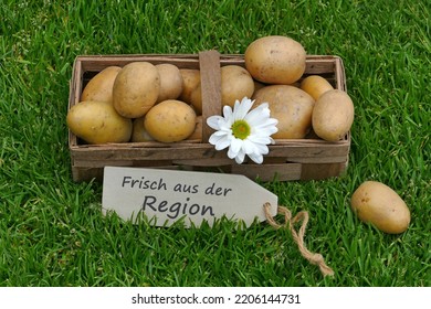 A basket of potatoes with the German text frisch aus der Region,frisch aus der Region means fresh from the region - Shutterstock ID 2206144731