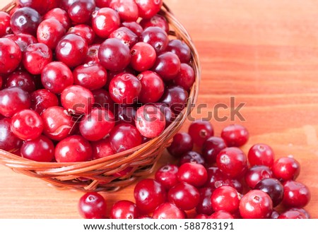 Basket with ripe cranberries on a wooden background