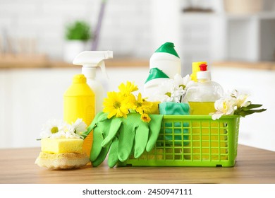 Basket with set of cleaning supplies and spring flowers on wooden table in kitchen - Powered by Shutterstock