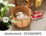 Basket with slippers for guests and sneakers in entryway at home