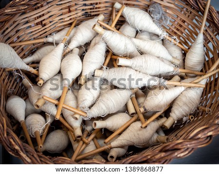 Basket with vintage reels with cotton threads ready for the processing on the cotton mill