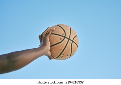 Basketball, Active And Sports Man Hand Holding Ball Showing Victory, Power Or Athletic Fitness From Below With Blue Sky Background. Player, Black Man Or Athlete Arm Practicing For Professional