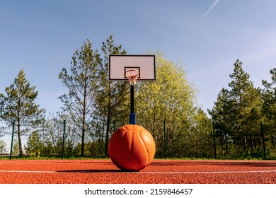 Basketball Ball In The Court On A Three Point Line,  Basket In The Background.