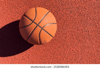 Basketball ball on the ground. Close-up ball on the red court. Basketball on the street or indoor court. Sports gear without people. Minimalism. Template, sport background  - Powered by Shutterstock