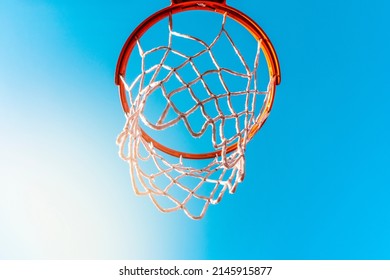 Basketball Basket Against A Blue Sky From A Low Angle.Low Angle Shot Of Basketball Hoop On Sunny Day Outside At Basketball Court In City Park.