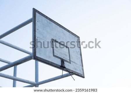 The basketball board is made of wood with a broken basket ring