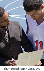 A Basketball Coach In A Business Suit Sharing A Play With A Player On The Team.   He Could Be Also Be Recruiter Trying To Get Him To Sign A Contract.