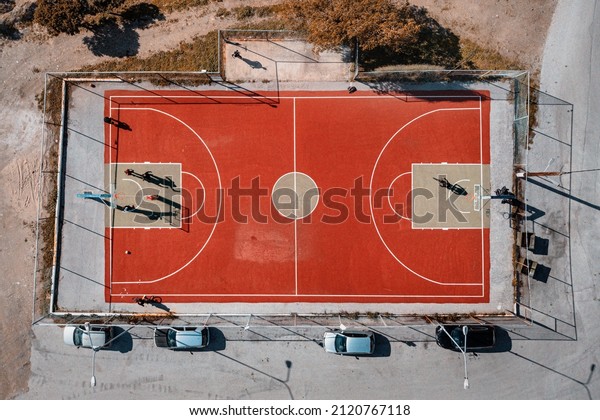 Basketball court in an urban suburb with parked\
cars, aerial view. The concept of district improvement and sports\
for young people